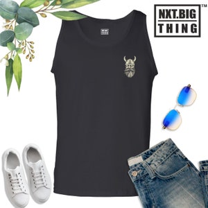 May include: Black sleeveless tank top with a white graphic of a viking helmet and beard with the word "DAD!" underneath. The tank top is on a white background with a pair of white sneakers, blue jeans, and sunglasses.