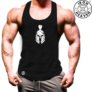 Puede incluir: Camiseta sin mangas negra con un diseño de casco espartano blanco. La camiseta sin mangas tiene un diseño de espalda nadadora y está hecha de un tejido suave y transpirable. El logotipo de Iron Heaven es visible en la esquina superior derecha.