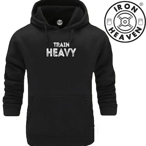 Peut inclure: Sweat-shirt à capuche noir avec un motif blanc qui dit "TRAIN HEAVY" et un petit logo sur le devant qui dit "IRON HEAVEN".