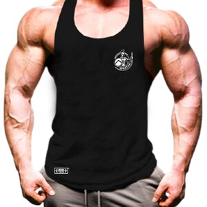 Puede incluir: Camiseta de tirantes negra sin mangas con un logotipo blanco de Spartan en la parte delantera. El logotipo presenta a un guerrero sosteniendo una lanza y un escudo. La camiseta de tirantes tiene una etiqueta blanca en la parte inferior que dice "Muscle Thing".