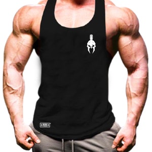 Pode incluir: Regata preta com um desenho de capacete espartano branco no peito. A regata sem mangas tem um decote redondo. Um pequeno logotipo retangular branco é visível no canto inferior esquerdo. Feita de um tecido macio e respirável.