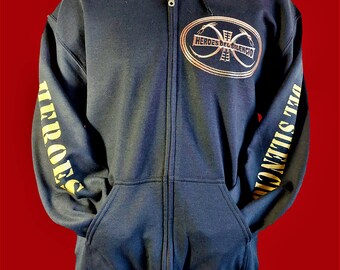 May include: Black zippered hoodie with a gold embroidered logo on the front that says "Heroes del Silencio". The sleeves have gold lettering that says "Heroes del Silencio" on the left sleeve and "Silencio" on the right sleeve.