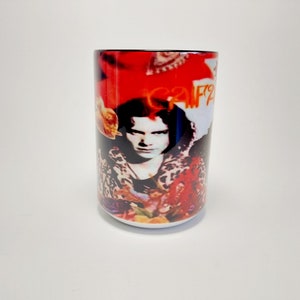 May include: White ceramic mug featuring a portrait of a person with long hair, set against a red and white background. The mug has a black rim and the text "CAF?2" is visible. The design includes floral and leopard print elements.