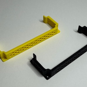 May include: Two 3D printed plastic brackets, one yellow and one black, with a honeycomb pattern. The brackets are designed to hold a computer component.