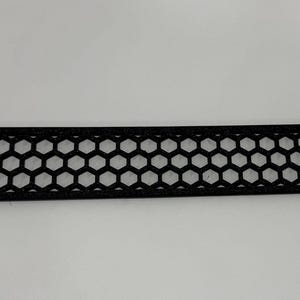 May include: A black rectangular vent cover with a honeycomb pattern. The vent cover has rounded corners and four mounting holes. The design is a series of interconnected hexagons, creating an open, airy appearance.