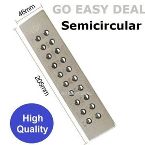 May include: A silver metal semicircular ring mandrel with a ruler on one side and 18 different sized holes for shaping rings. The ruler is marked in millimeters and the mandrel is 20.5 cm long and 4.6 cm wide.