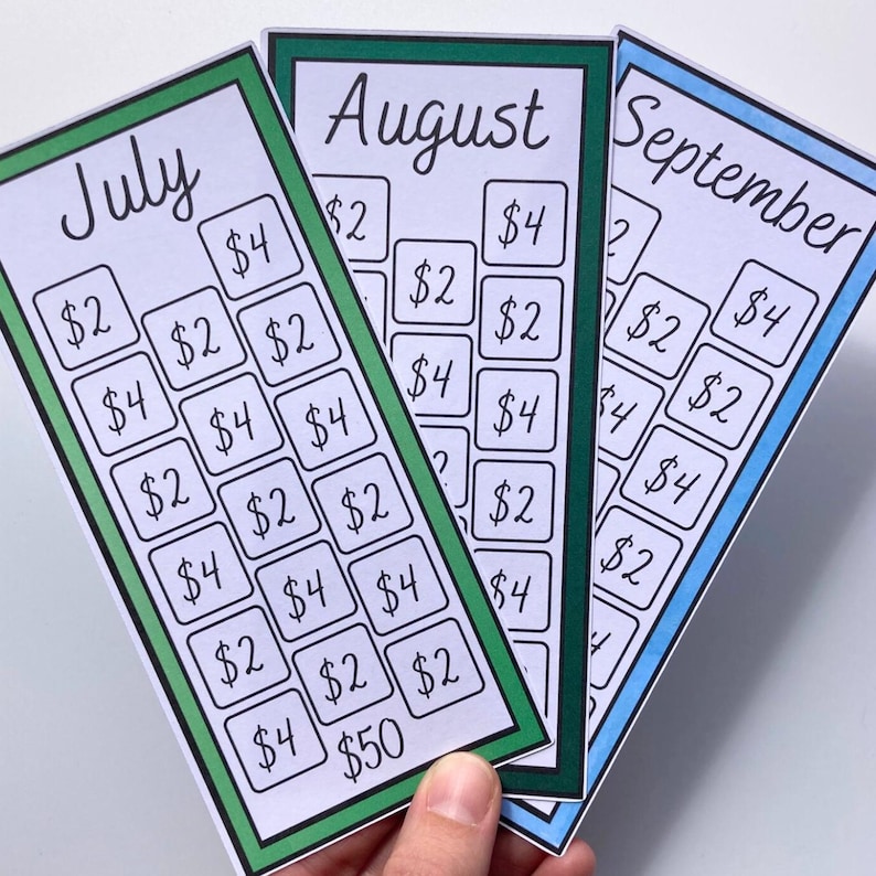 May include: Three colorful savings tracker cards for July, August, and September. Each card has a different colored border and features a grid of boxes with dollar amounts. The cards are held by a hand.