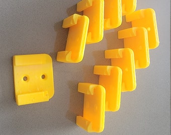 May include: A set of ten yellow plastic wall mounts, designed for mounting objects. The mounts have a rectangular shape with two holes on the top and a small lip on the bottom.
