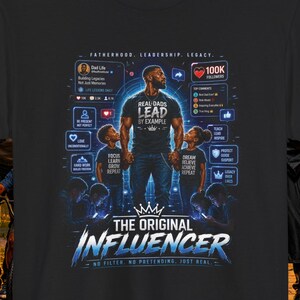 May include: A black t-shirt featuring a graphic print of a man standing between two children. The design includes social media interface elements, the text "REAL DADS LEAD BY EXAMPLE," "THE ORIGINAL INFLUENCER," and "NO FILTER. NO PRETENDING. JUST REAL."