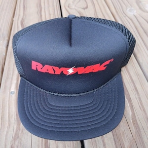 May include: Black trucker hat with the red text "RAYOVAC" and a lightning bolt graphic. The hat has a black mesh back and a curved brim. A black cord runs along the base of the front panel.
