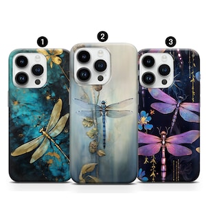Peut inclure: Trois coques d'iPhone avec des motifs de libellules différents. La première coque a un fond bleu et vert avec une libellule dorée. La deuxième coque a un fond bleu et blanc avec une libellule bleue. La troisième coque a un fond noir avec une libellule violette.