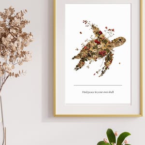 Könnte beinhalten: Gerahmter Kunstdruck mit einer Schildkrötensilhouette aus getrockneten Blumen in Braun-, Rot- und Gelbtönen. Der Druck enthält den Text "Find peace in your own shell". Der Rahmen ist goldfarben.