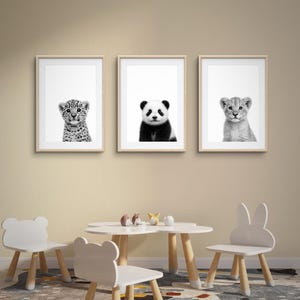 Könnte beinhalten: Drei gerahmte Schwarz-Weiß-Tierporträts: ein Leopardenjunges, ein Panda und ein Löwenjunges. Darunter ein weißer Tisch mit bärenförmigen Stühlen und einem hasenförmigen Stuhl. Der Raum hat ein neutrales Farbschema.