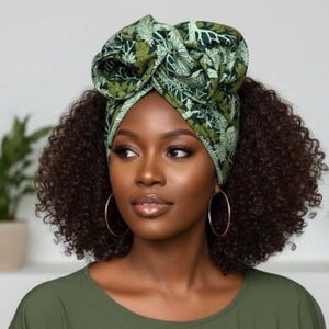 May include: A woman wearing a green and white patterned head wrap. The head wrap is tied in a large bow on top of the head. The woman is wearing gold hoop earrings and a green top. Her hair is curly and dark brown.