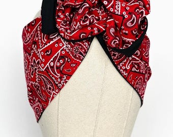 May include: Red bandana headband with a large bow, featuring a paisley pattern. The headband is trimmed with black fabric.