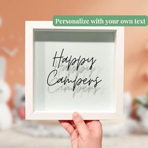 May include: White picture frame with a glass front. The frame has a black inscription that reads "Happy Campers".