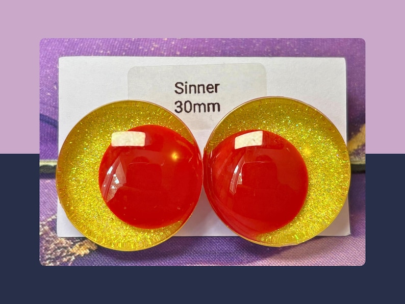 May include: A pair of circular earrings featuring a bright yellow glitter base with a smooth, solid red circular accent layered on top. The white display card behind the earrings is printed with the text Sinner 30mm, indicating the size.