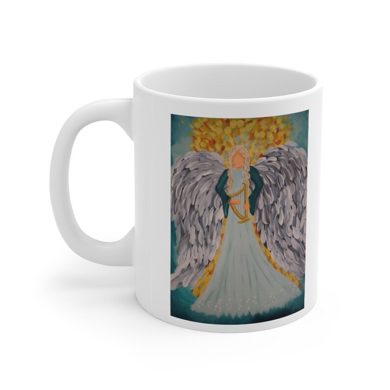 Puede incluir: Taza de cer&aacute;mica blanca con una ilustraci&oacute;n colorida de un &aacute;ngel con alas tocando un arpa. El &aacute;ngel lleva un vestido azul y una chaqueta turquesa. El fondo es un cielo azul con nubes amarillas y naranjas.