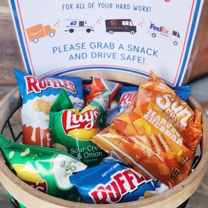 May include: A basket containing packets of crisps, such as Ruffles and Lays, with a sign above. The sign says "To Our Awesome Delivery Drivers, Thank You for All of Your Hard Work! Please Grab a Snack and Drive Safe!"