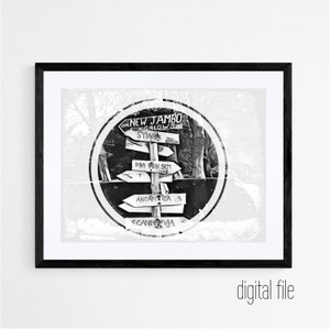 Könnte beinhalten: Schwarzweißfoto eines Wegweisers mit Pfeilen, die in verschiedene Richtungen zeigen. Der Wegweiser steht vor einem Wald und trägt die Aufschrift "New Jambo" und "Sydney".