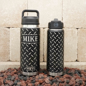 May include: Two black stainless steel water bottles with diamond plate pattern and silver accents. The larger bottle has a black handle and the text "MIKE" and "YETI" on the front.