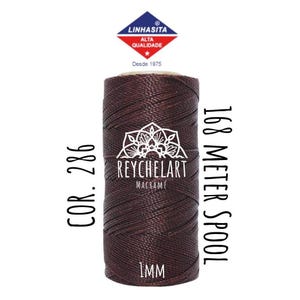 Könnte beinhalten: Ein braunes 1 mm dickes Garn für Makramee, 168 Meter Spule, Farbe 286. Die Spule ist mit "ReycheLart Macrame" und "Linhasita Alta Qualidade Desde 1975" beschriftet.