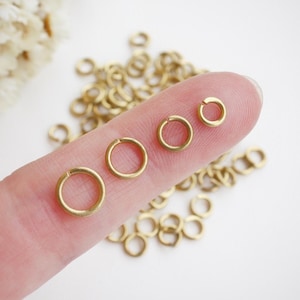 Peut inclure: Un ensemble de quatre anneaux de saut dorés de différentes tailles, présentés sur un doigt.