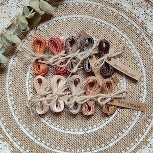 May include: A set of 12 embroidery floss spools in shades of brown, orange, and beige. The spools are tied together with twine and have tags that say "REYCHELART".