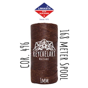 Può includere: Un rocchetto di corda da macramè marrone da 1 mm di spessore con 168 metri di corda. Il rocchetto è etichettato "COR. 496" e "REYCHELART MACRAMÊ".