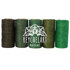 Può includere: Cinque bobine di cordoncino di cotone verde, disposte in un gradiente dal verde scuro al verde chiaro. Le bobine sono etichettate "REYCHELART MACRAMÉ".