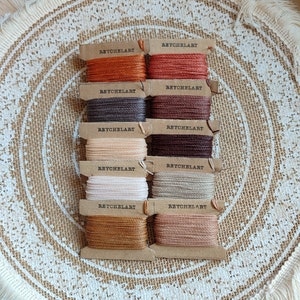 May include: Eight spools of embroidery floss in various shades of brown, beige, and cream. Each spool is labeled "REYCHELART".