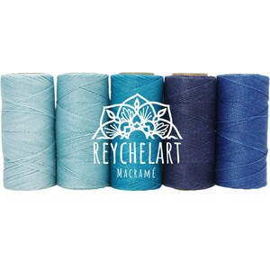 Peut inclure: Cinq bobines de cordon en coton dans des tons de bleu, du bleu clair au bleu foncé. Les bobines sont disposées en dégradé du plus clair au plus foncé. Le texte "REYCHELART MACRAMÉ" est imprimé en blanc sur un motif de mandala blanc au centre de l'image.