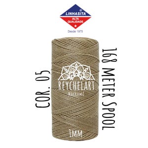 以下が含まれることがあります： 1 mm 厚のナチュラルブラウンコードのスプールで、「168 Meter Spool」と「Cor. 05」のラベルが付いています。スプールは ReycheLart Macrame 製で、「Linhasita Alta Qualidade」のラベルが付いており、星と「Desde 1975」の文字が書かれています。