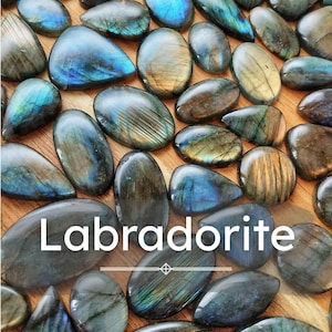 May include: A selection of polished labradorite stones in different shapes. The stones show iridescent flashes of blue, green, and gold against a dark grey background. The word "Labradorite" is displayed in white text.