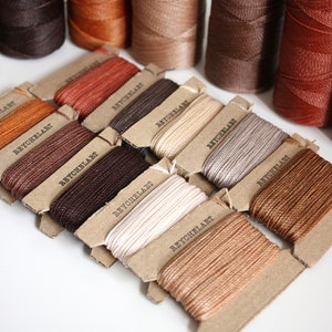 May include: Assortment of spools of waxed thread in various shades of brown, beige, and white. Each spool is labeled "REYCHELART".