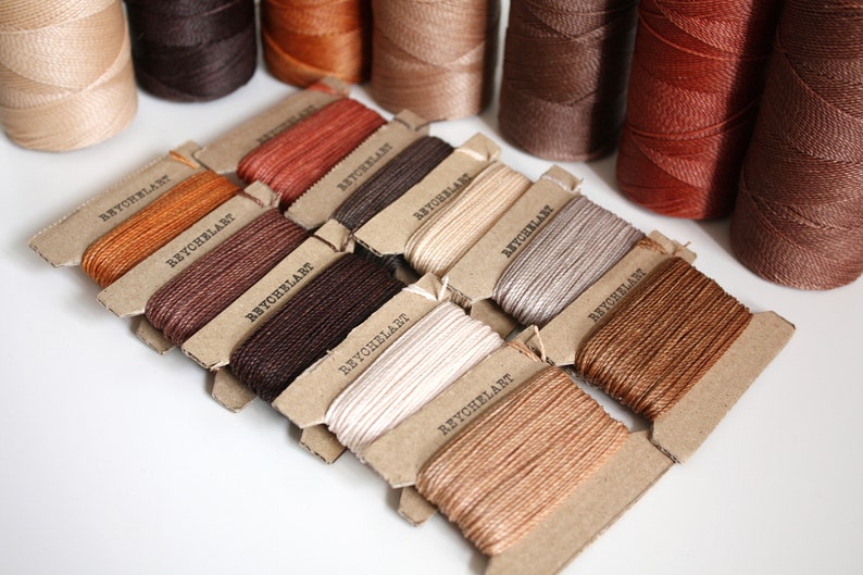 May include: Assortment of spools of waxed thread in various shades of brown, beige, and white. Each spool is labeled "REYCHELART".