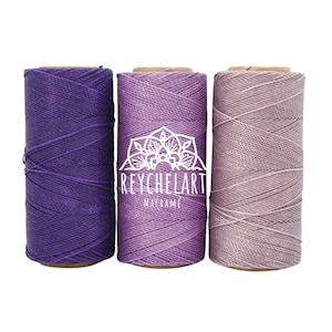 Könnte beinhalten: Drei Spulen Baumwollschnur in den Farben Lila, Lavendel und Rosa. Die Schnur ist perfekt für Makramee-Projekte.