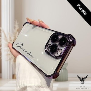 May include: Clear phone case with a purple bumper and camera ring. The case has the name "Quentin" in a handwritten font. The word "Purple" is printed on a black diagonal stripe. The Cozy Workshops logo is in the bottom right corner.