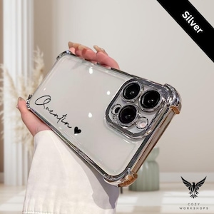 May include: Clear phone case with silver accents and the name "Quentin" in black script, followed by a black heart. The case has a silver frame and a clear back, with a "Silver" label in the corner.