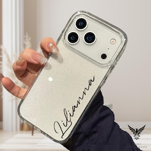 May include: Clear phone case with a glittery white back and the name "Lilianna" in black script. The case has a clear border and a camera cutout. The phone case is held in a hand.