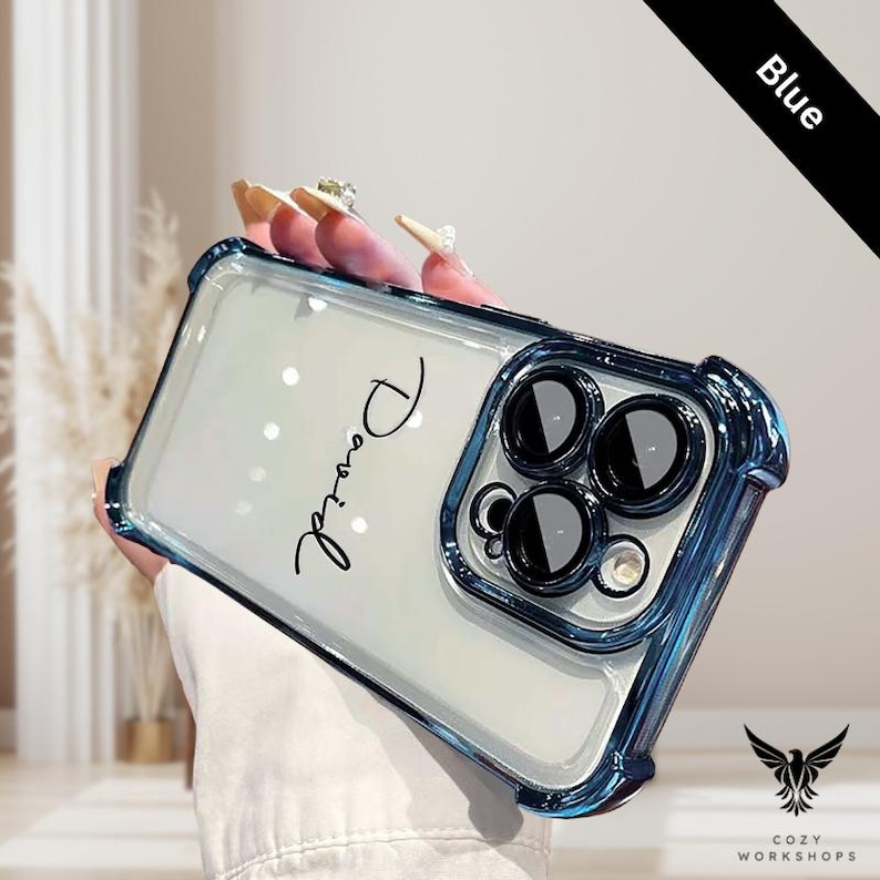 May include: A clear phone case with a blue bumper. The case has the name "David" in cursive script. The phone case has a black bar that says "Blue". The case has a logo that says "Cozy Workshops".