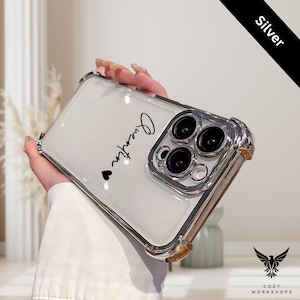 May include: Clear phone case with silver accents and the name "Quentin" in black script, followed by a small heart. The case has a protective silver border around the camera lenses and a silver frame. The word "Silver" is printed on a black diagonal banner.