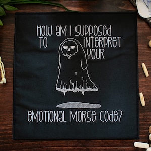 May include: Black fabric patch with white embroidery depicting a ghost with a skull face and the text "How am I supposed to interpret your emotional Morse code?"