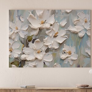 A painting of white flowers with a textured, 3D effect, displayed above a wooden shelf adorned with small decorative items