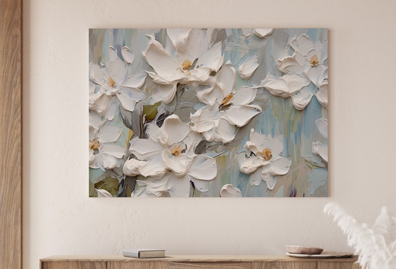 A painting of white flowers with a textured, 3D effect, displayed above a wooden shelf adorned with small decorative items