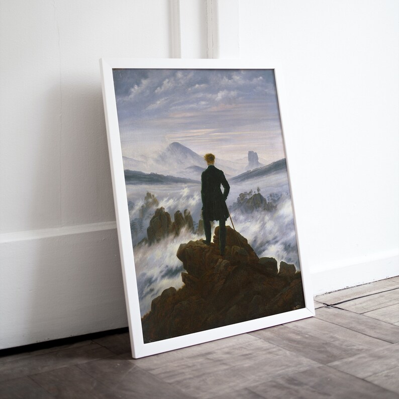 May include: A framed painting depicting a man standing on a mountaintop overlooking a sea of clouds. The sky is a pale blue with wispy clouds. The man is wearing a dark coat and has his back to the viewer. The painting is in a white frame.