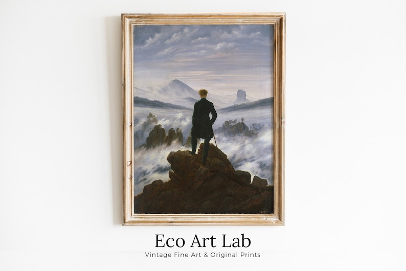 May include: A framed painting depicting a man standing on a rocky outcrop overlooking a sea of clouds. The sky is a pale blue with wispy clouds. The man is wearing a dark coat and has his back to the viewer. The painting is in a simple wooden frame.