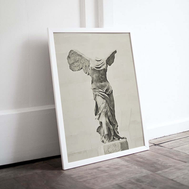 May include: A black and white photograph of the Winged Victory of Samothrace statue, a famous Greek sculpture. The statue is displayed in a white frame.
