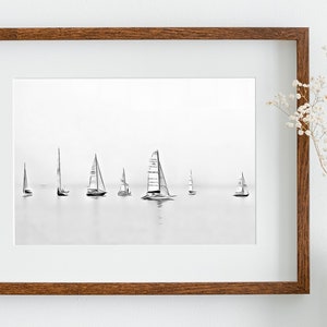 K&ouml;nnte beinhalten: Ein gerahmtes Schwarzwei&szlig;foto von Segelbooten auf dem Wasser. Die Segelboote sind vor einem hellgrauen Himmel silhouettiert.