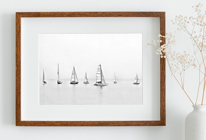 K&ouml;nnte beinhalten: Ein gerahmtes Schwarzwei&szlig;foto von Segelbooten auf dem Wasser. Die Segelboote sind vor einem hellgrauen Himmel silhouettiert.